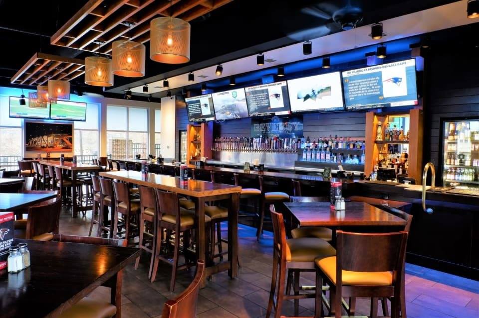 Interior of restaurant with blue bar with flat screen tvs and wooden chairs