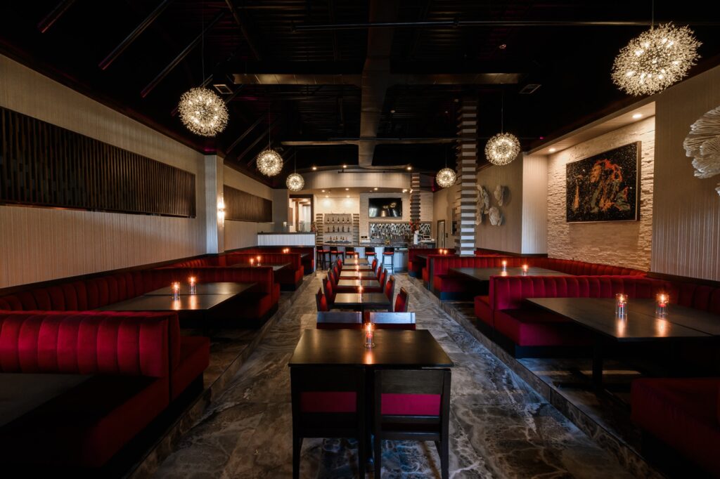 Plush red sofas, dark wooden tables, art covered cream walls at Continent Restaurant