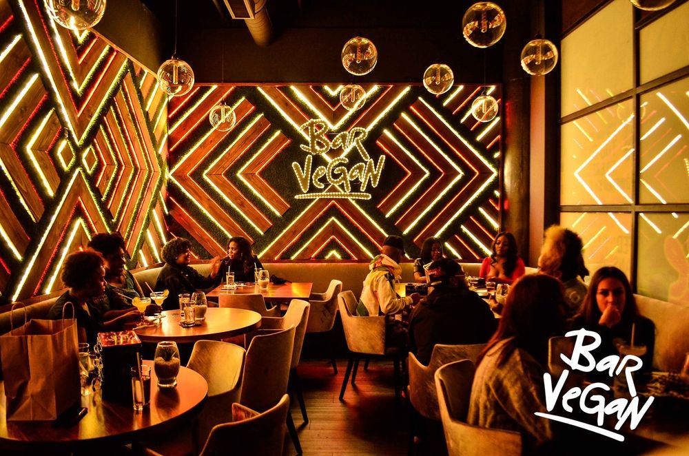 Indoors at Vegan Bar with animated lights casting a golden glow on customers' faces
