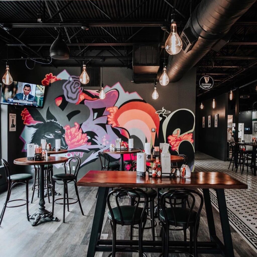 Interior of restaurant with graffiti covered walls and dark furniture at The BQE Restaurant & Lounge
