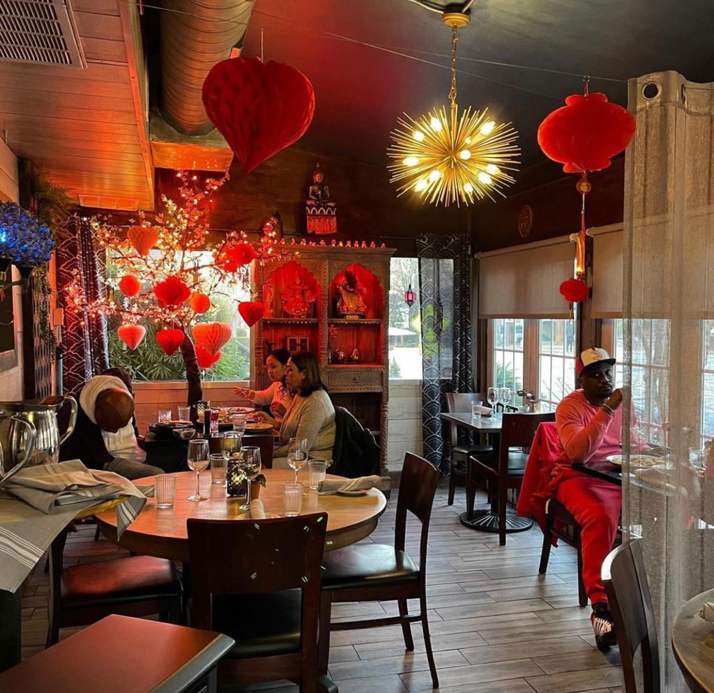 Red decorative pieces adorning restaurant with wooden furniture and cream walls at Poor Calvin's