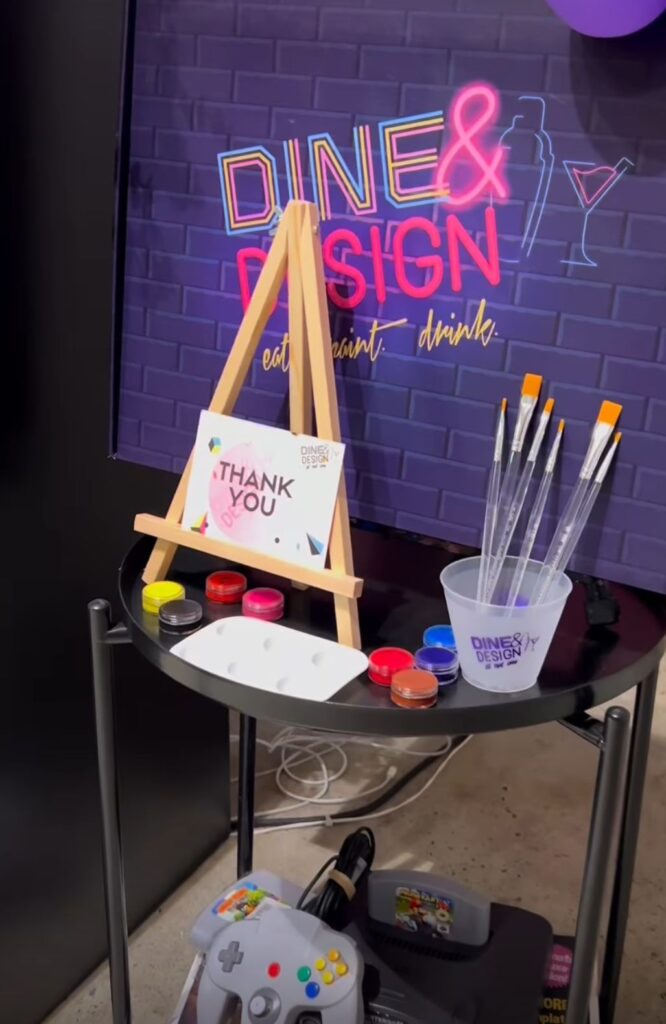 Canvas and paint brushes against purple brick wall at Dine & Design