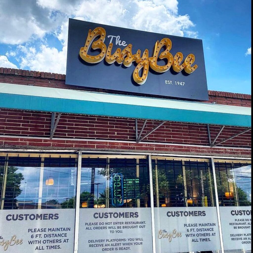 Busy Bee sign above a blue awning attached to the exterior of a brick edifice at Busy Bee Café