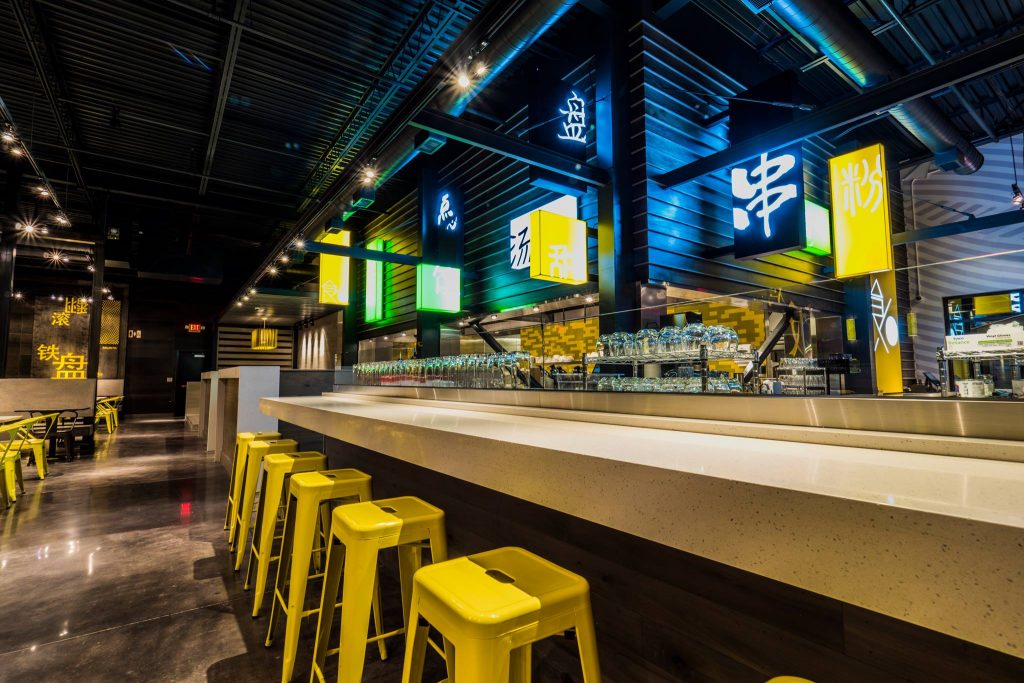 Yellow stools surrounding a beige bar at Food Terminal
