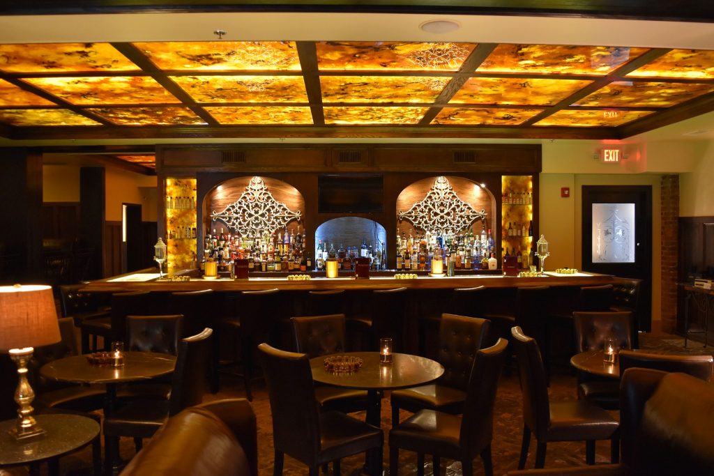 Closeup shot of restaurant bathed in golden light and furnished with wooden chairs and tables at red Phone Booth