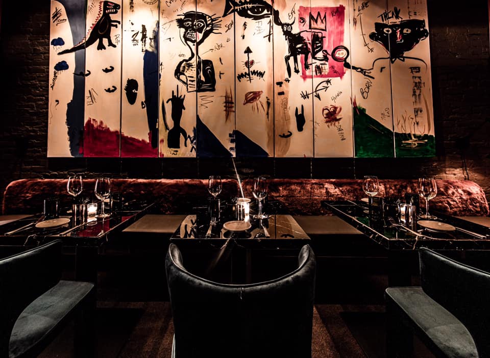 Leather armchairs and glass tables arranged against art covered wall