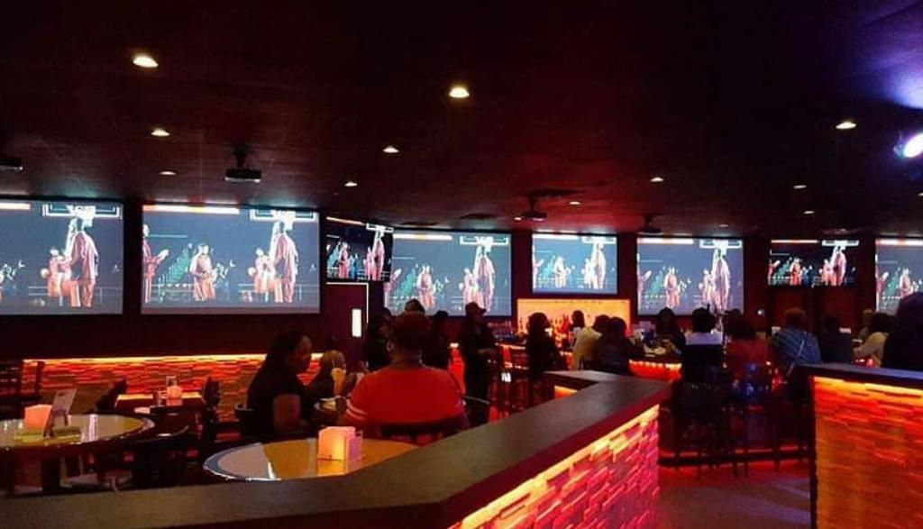 Patrons seated at a dimly lighted restaurant with a chrome bar at Sudo Bar and Grill